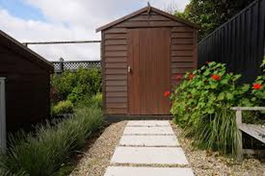 Stepping-stone garden path leading through planting to a timber shed